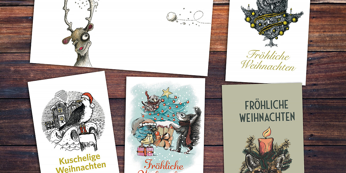 Fünf Weihnachtskarten mit verschiedenen Motiven auf einem Holztisch