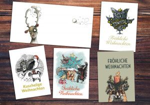 Fünf Weihnachtskarten mit verschiedenen Motiven auf einem Holztisch