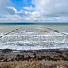 Im Vordergrund das Hohe Ufer, Richtung Horizont das stürmische Meer. Im oberen Drittel ein wolkenverhangener blauer Himmel.