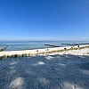 Blick auf das stille Meer mit Buhnen, im Vordergrund Sandstrand