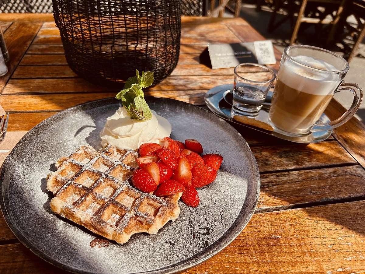 Im oberen Drittel des Bildes Himmel mit weißen Wolken, die folgenden zwei Drittel: nasser Strand auf dem sich der Himmel spiegelt.