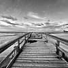 Schwarzweiß-Aufnahme der Ostsee. Blick auf einen langen Holzsteg.