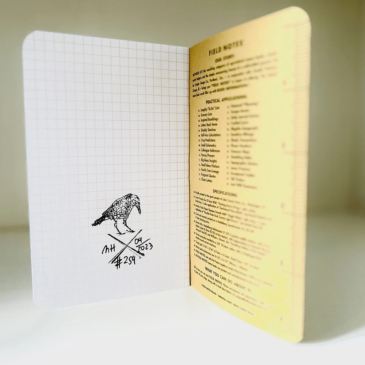Foto eines stehenden und aufgeklappten Field Notes Heftes. Auf der linken Seite ist auf kariertem Papier der Stempel mit der Nummer 254 zu sehen.