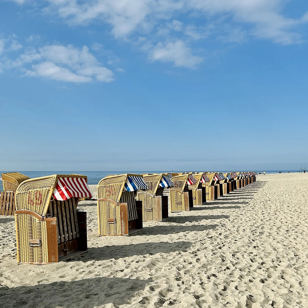 Standkörbe auf Sandstrand bei blauem Himmel im Sonnenschein