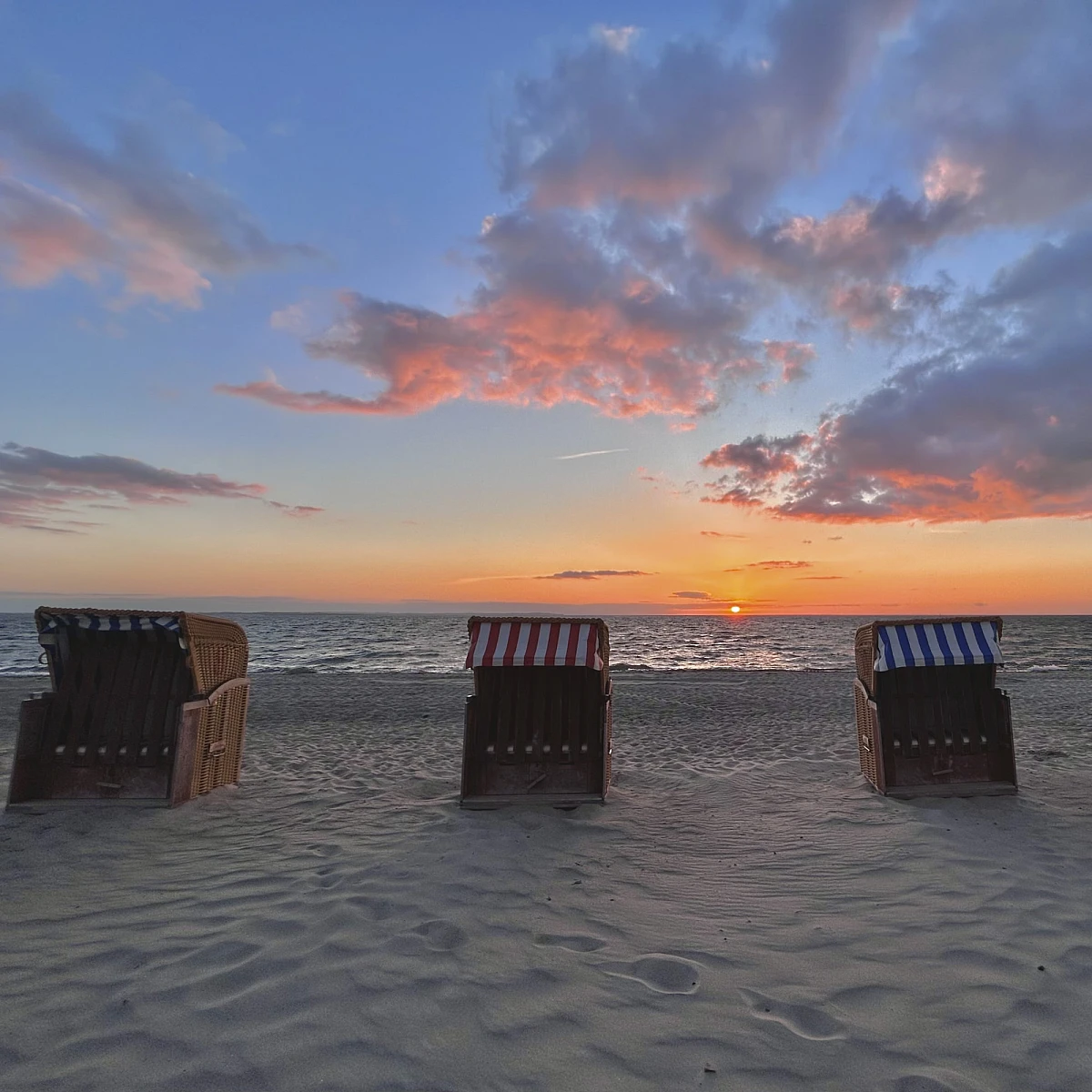 Standkörbe auf Sandstrand bei blauem Himmel im Sonnenschein