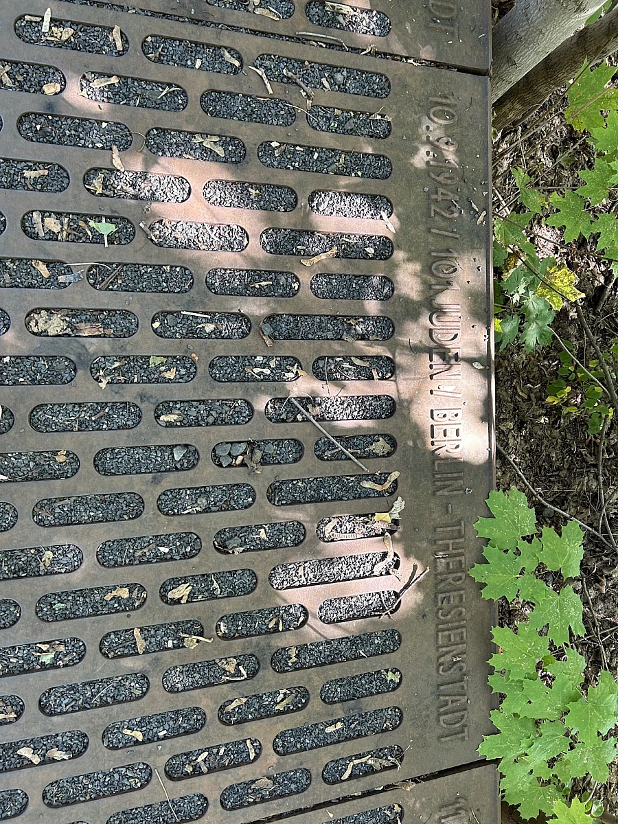 Aus einer Seilbahngondel nach unten fotografiert: Jeans und Sneaker über einer Wiese. Im Hintergrund und Tal Häuser und Felder.