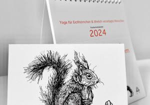Der Kalender "Ommmmmmmmmmmm - Yoga für Eichhörnchen & ähnlich veranlagte Menschen - Postkartenkalender 2024"  steht aufgeklappt auf einer weißen Fläche. Im Vordergrund eine abgetrennte Postkarte.