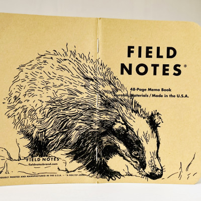 Ein aufgeklapptes Field Notes Heft auf dessen Rücken aus Kraft-Papier sich die schwarze Zeichnung eines Dachses befindet.