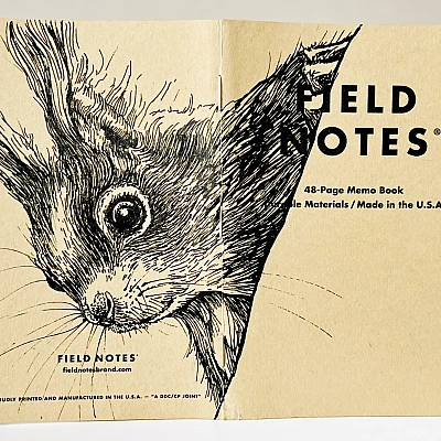 Ein aufgeklapptes Field Notes Heft auf dessen Rücken aus Kraft-Papier sich die schwarze Zeichnung eines Eichhörnchenkopfes erstreckt.