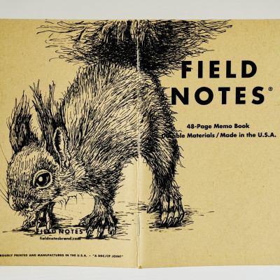 Ein aufgeklapptes Field Notes Heft auf dessen Rücken aus Kraft-Papier sich die Zeichnung eines Eichhörnchens befindet.