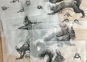Viele Blätter Transparentpapier mit Tintezeichnungen liegen übereinander auf einem Holztisch.